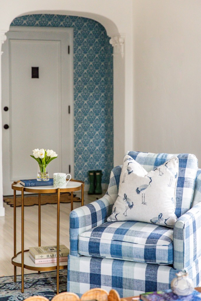 gingham chair in white and patterned room with side table and flowers
